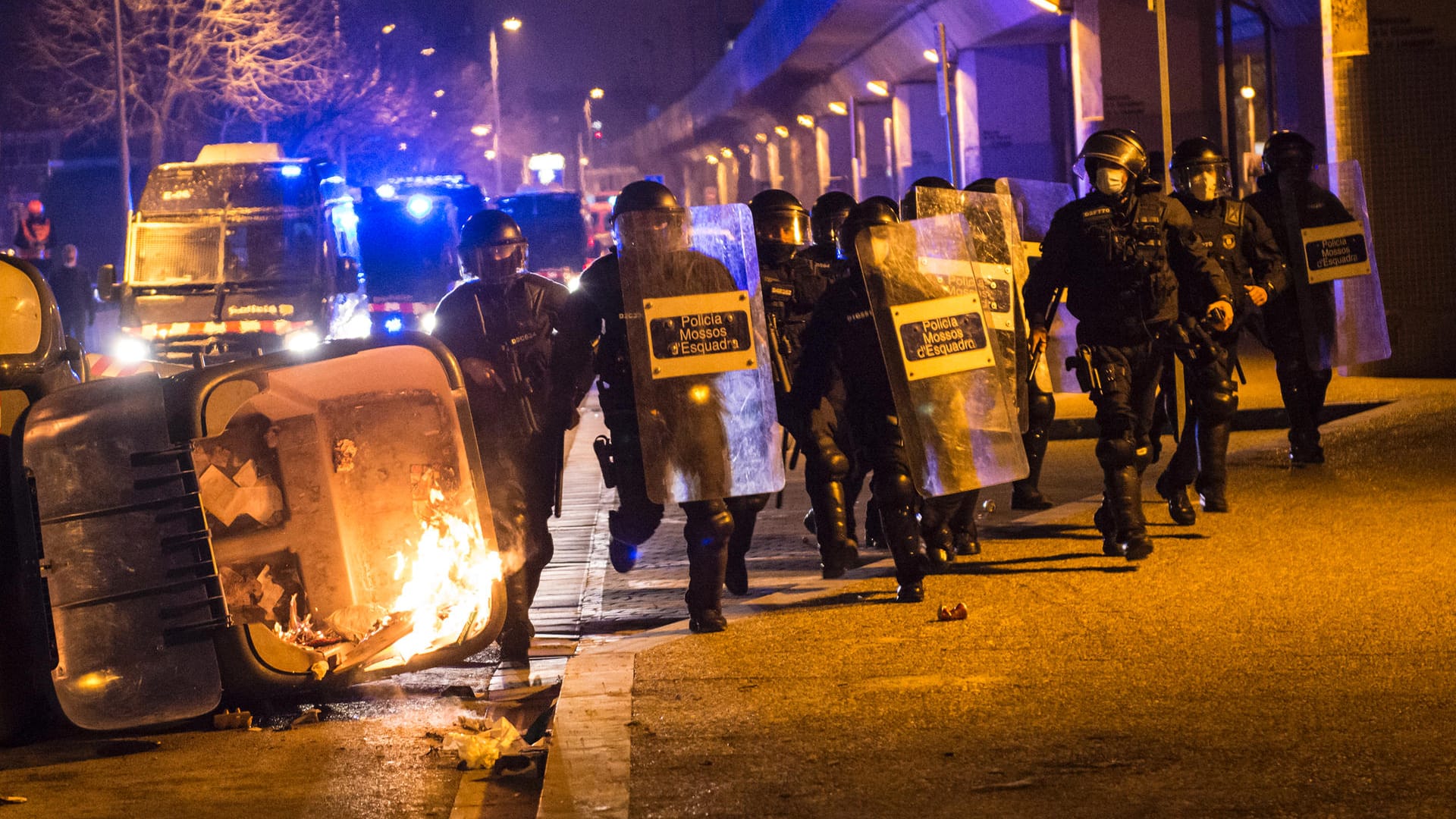 Spanische Bereitschaftspolizisten laufen an brennenden Mültonnen in der Stadt Gerona vorbei. Die Proteste gegen die Festnahme des Rappers wegen Beleidigung des Königshauses dauern vier Tage an.