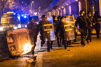 Spanische Bereitschaftspolizisten laufen an brennenden Mültonnen in der Stadt Gerona vorbei. Die Proteste gegen die Festnahme des Rappers wegen Beleidigung des Königshauses dauern vier Tage an.