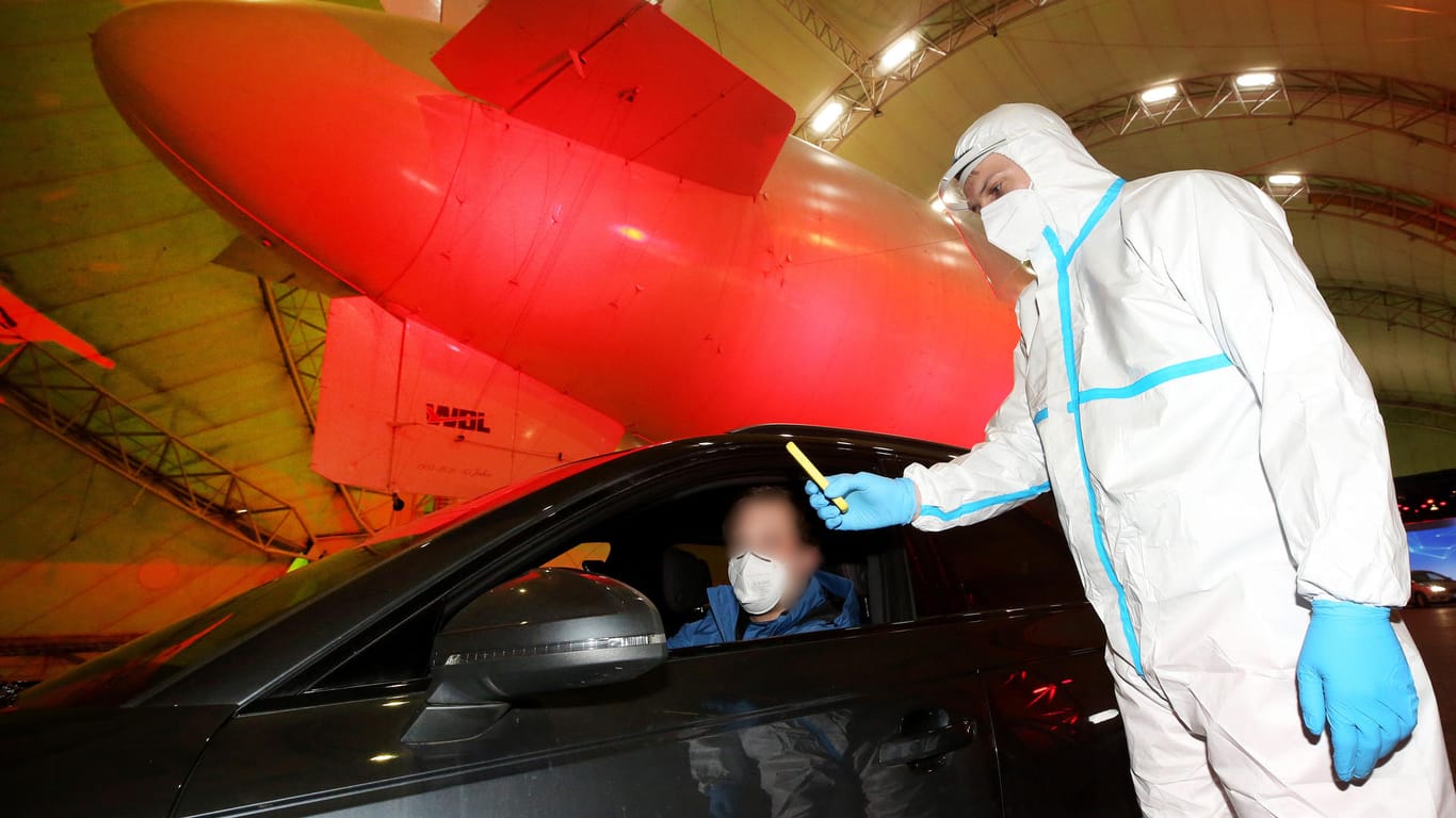 Im Luftschiffhangar des Flughafens Essen/Mülheim führt ein Rote Kreuz-Mitarbeiter im Drive-In-Testzentrum einen Corona-Schnelltest durch.