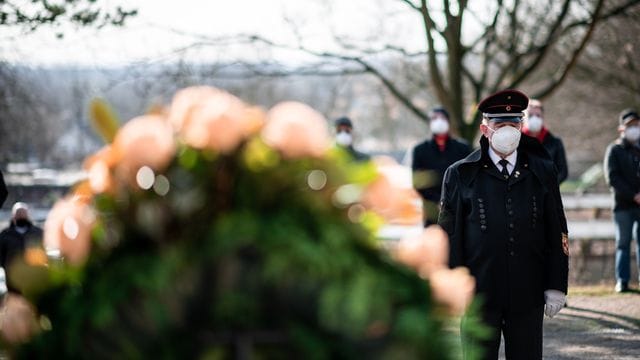 Ein Bergmann steht vor einem Kranz am Ehrenmal auf dem Friedhof in Bergkamen.