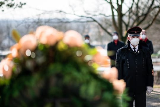 Ein Bergmann steht vor einem Kranz am Ehrenmal auf dem Friedhof in Bergkamen.