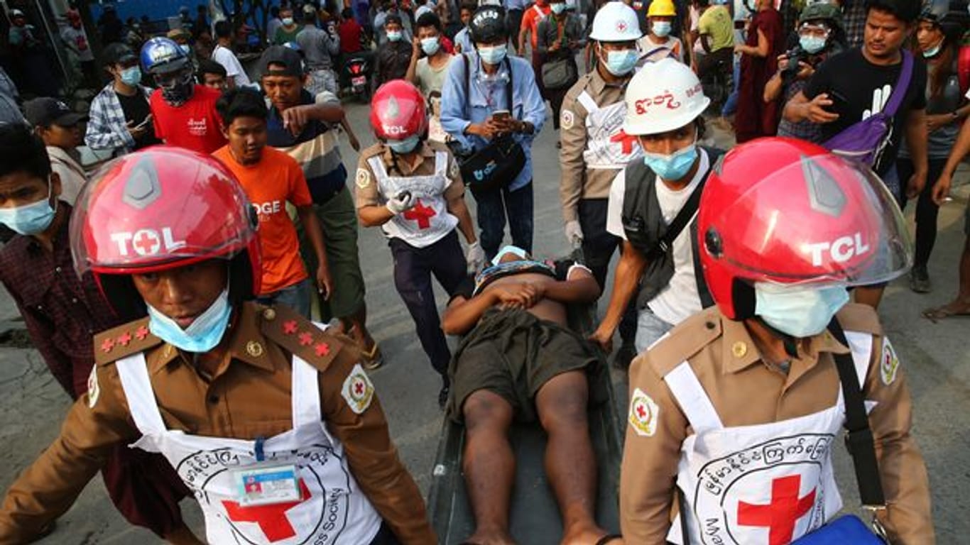 Helfer des Roten Kreuzes tragen einen Verletzten von einer Demonstration gegen den Putsch weg.