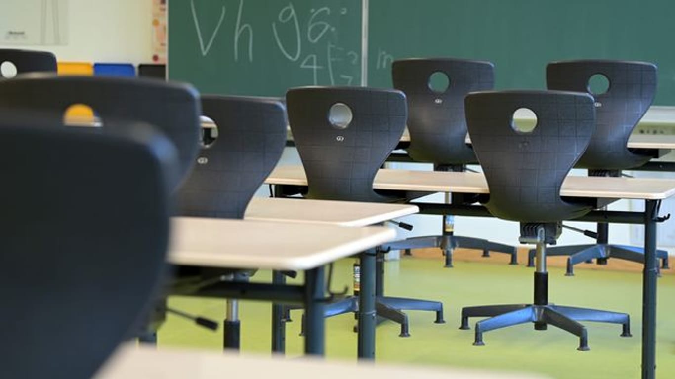 In einem leeren Klassenzimmer sind die Stühle auf die Schulbänke gestellt.