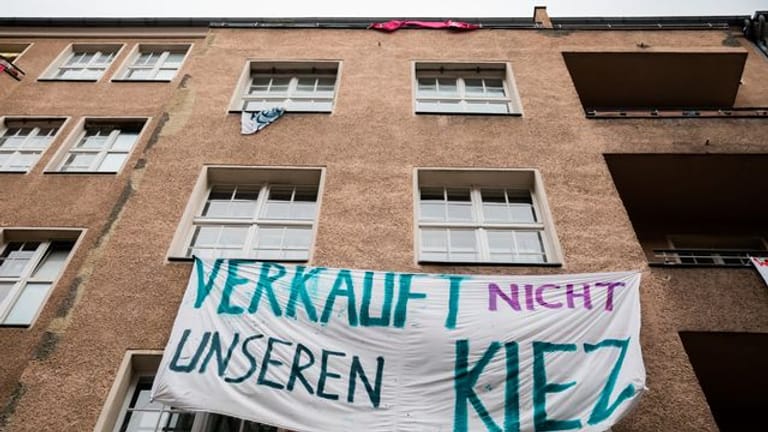Ein Transparent gegen Investoren und Gentrifizierung hängt an der Fassade eines Hauses in Berlin-Neukölln.