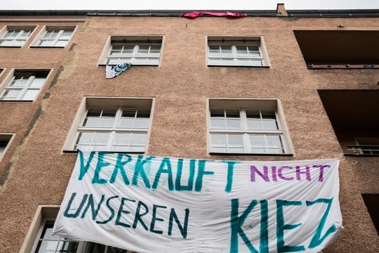 Ein Transparent gegen Investoren und Gentrifizierung hängt an der Fassade eines Hauses in Berlin-Neukölln.