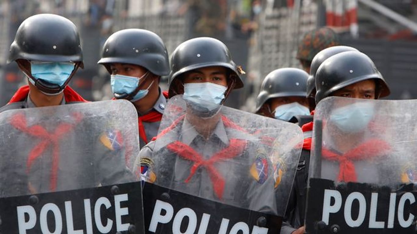 Polizisten am Rande einer Anti-Putsch-Demonstration in Mandalay hinter einer Strassenbarrikade.