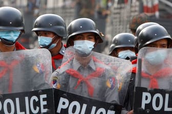 Polizisten am Rande einer Anti-Putsch-Demonstration in Mandalay hinter einer Strassenbarrikade.