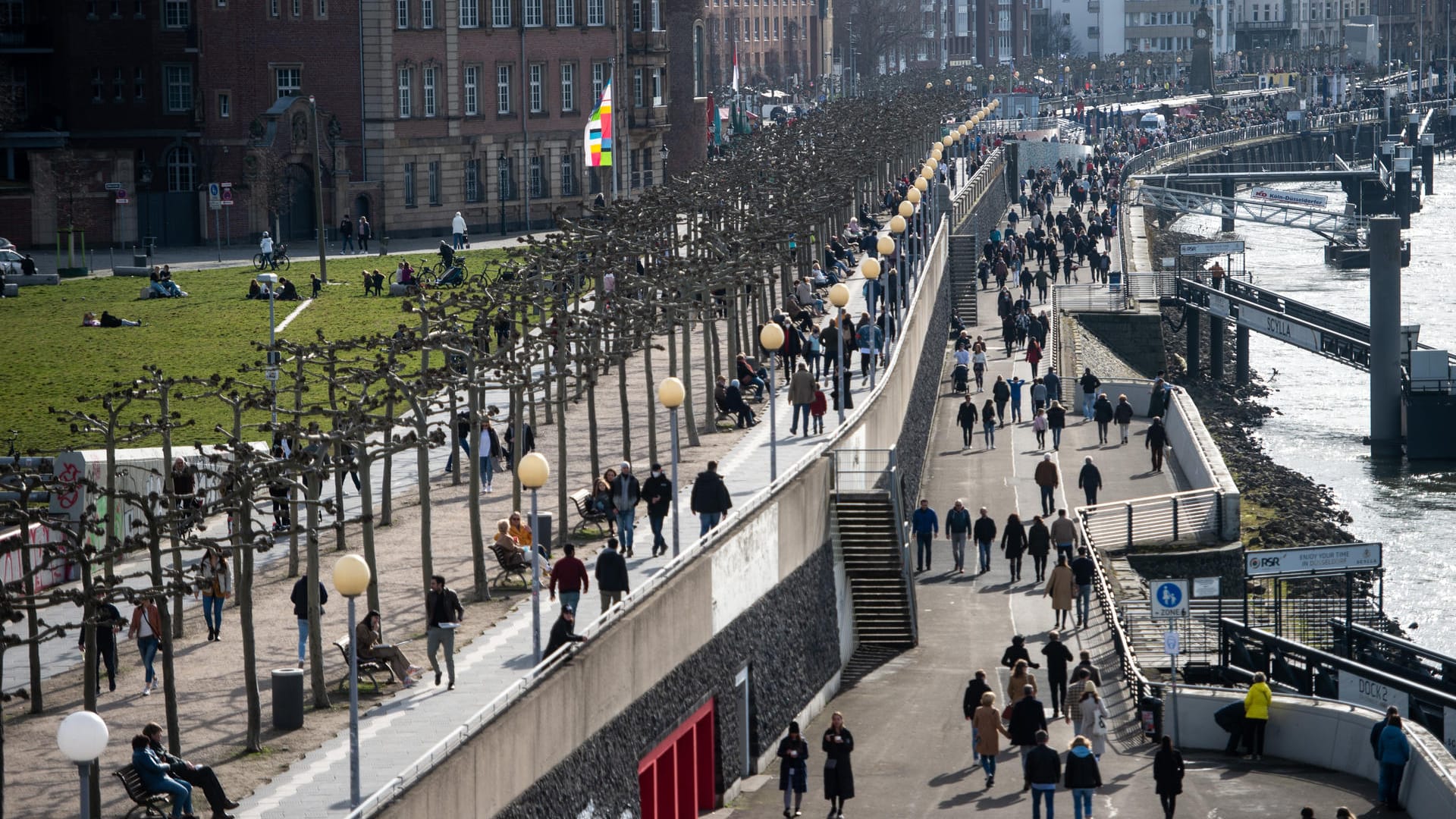 Zahlreiche Menschen gehen bei Sonnenschein und frühlingshaften Temperaturen auf der Rheinuferpromenade: Es kam zu größeren Menschenansammlungen.