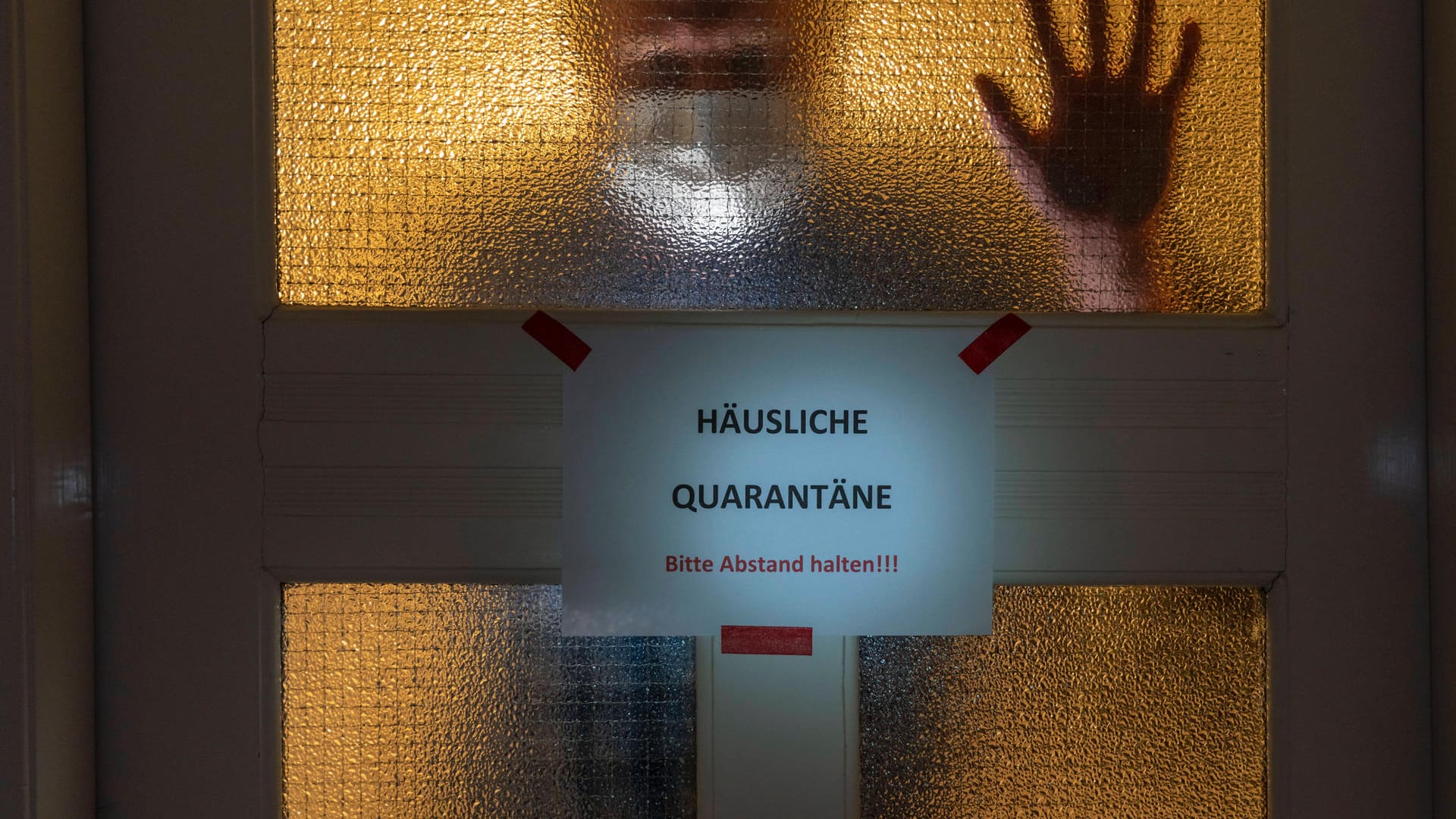 Ein Mann in Quarantäne steht hinter seiner Wohnungstür (Symbolbild): Für unseren Autoren waren Lebensmittel- und Medikamenten-Lieferungen von Freunden die einzigen Kontakte.