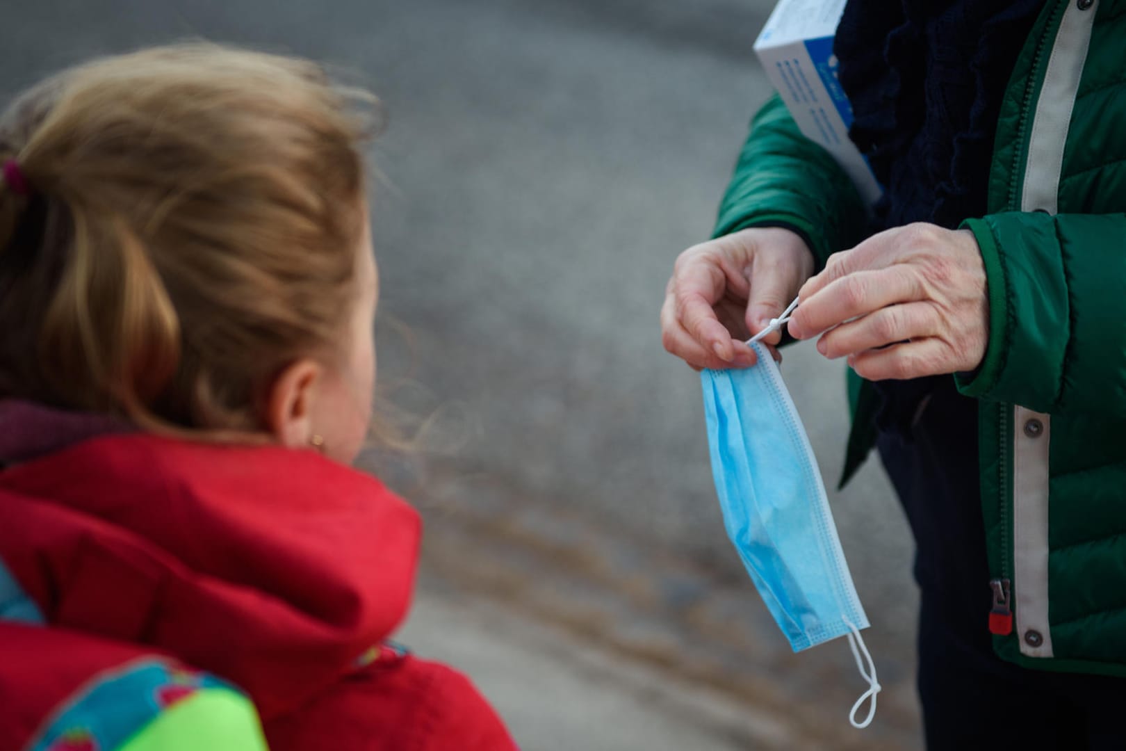 Eine Lehrerin kürzt einen Mund-Nasen-Schutz für eine Schülerin (Symbolbild): Für einen Teil der Schüler ging es am Montag zurück in die Schulen.