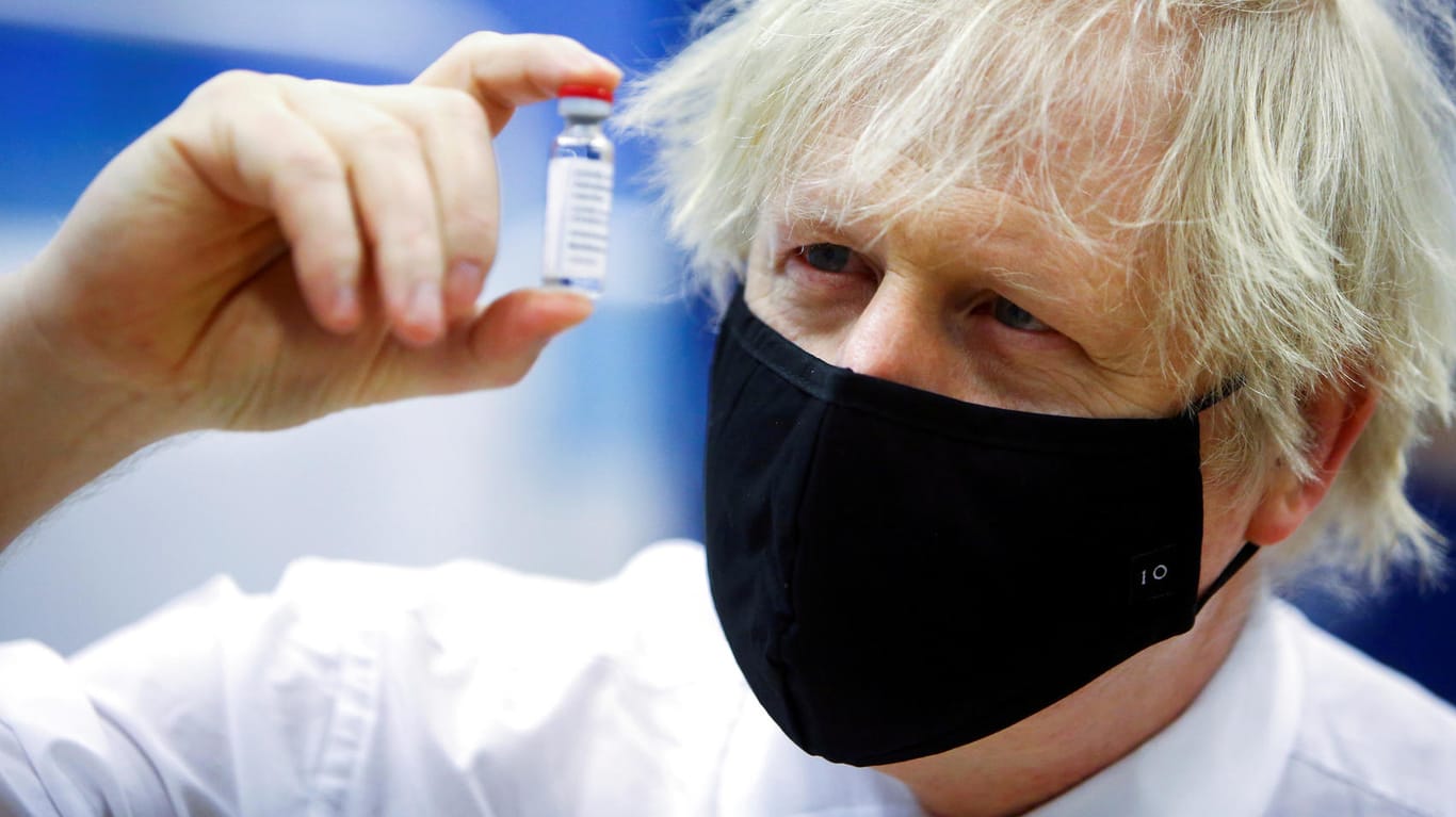 Premierminister Boris Johnson hält ein Fläschchen Astrazeneca-Impfstoff in der Hand: Er tastet sich vorsichtig aus dem Lockdown, trotz Druck von Außen.