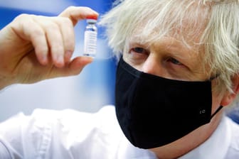 Premierminister Boris Johnson hält ein Fläschchen Astrazeneca-Impfstoff in der Hand: Er tastet sich vorsichtig aus dem Lockdown, trotz Druck von Außen.