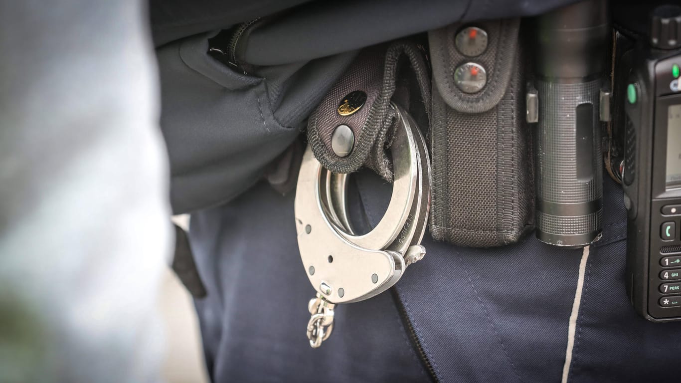 Beamter mit Handschellen am Gürtel (Symbolbild): In Köln ist ein Mann festgenommen worden, dem sexueller Missbrauch von Kindern vorgeworfen wird.