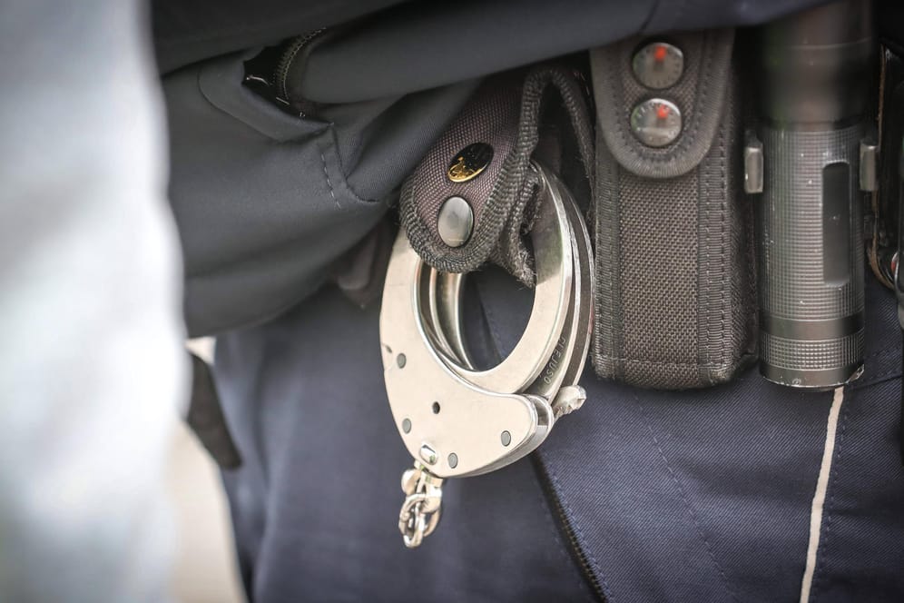 Beamter mit Handschellen am Gürtel (Symbolbild): In Köln ist ein Mann festgenommen worden, dem sexueller Missbrauch von Kindern vorgeworfen wird.