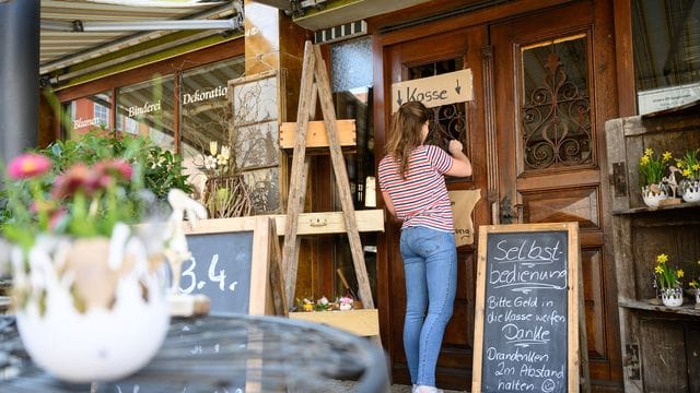 Eine Frau kauft bei einem Blumenladen an der Selbstbedienungskasse ein. Eine Frau kauft bei einem Blumenladen an der Selbstbedienungskasse ein.