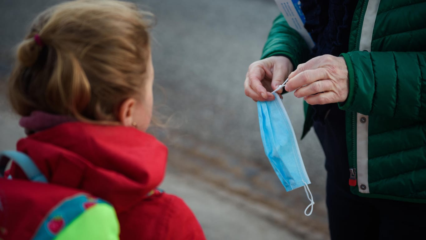 Kiel: Eine Lehrerin der Grundschule Russee kürzt einen Mund-Nasen-Schutz für eine Schülerin.