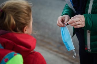 Kiel: Eine Lehrerin der Grundschule Russee kürzt einen Mund-Nasen-Schutz für eine Schülerin.