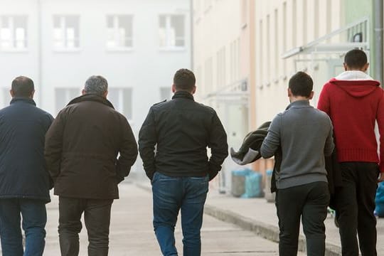 Männliche Asylbewerber gehen über das Gelände der Zentralen Ausländerbehörde (ZABH) in Eisenhüttenstadt.