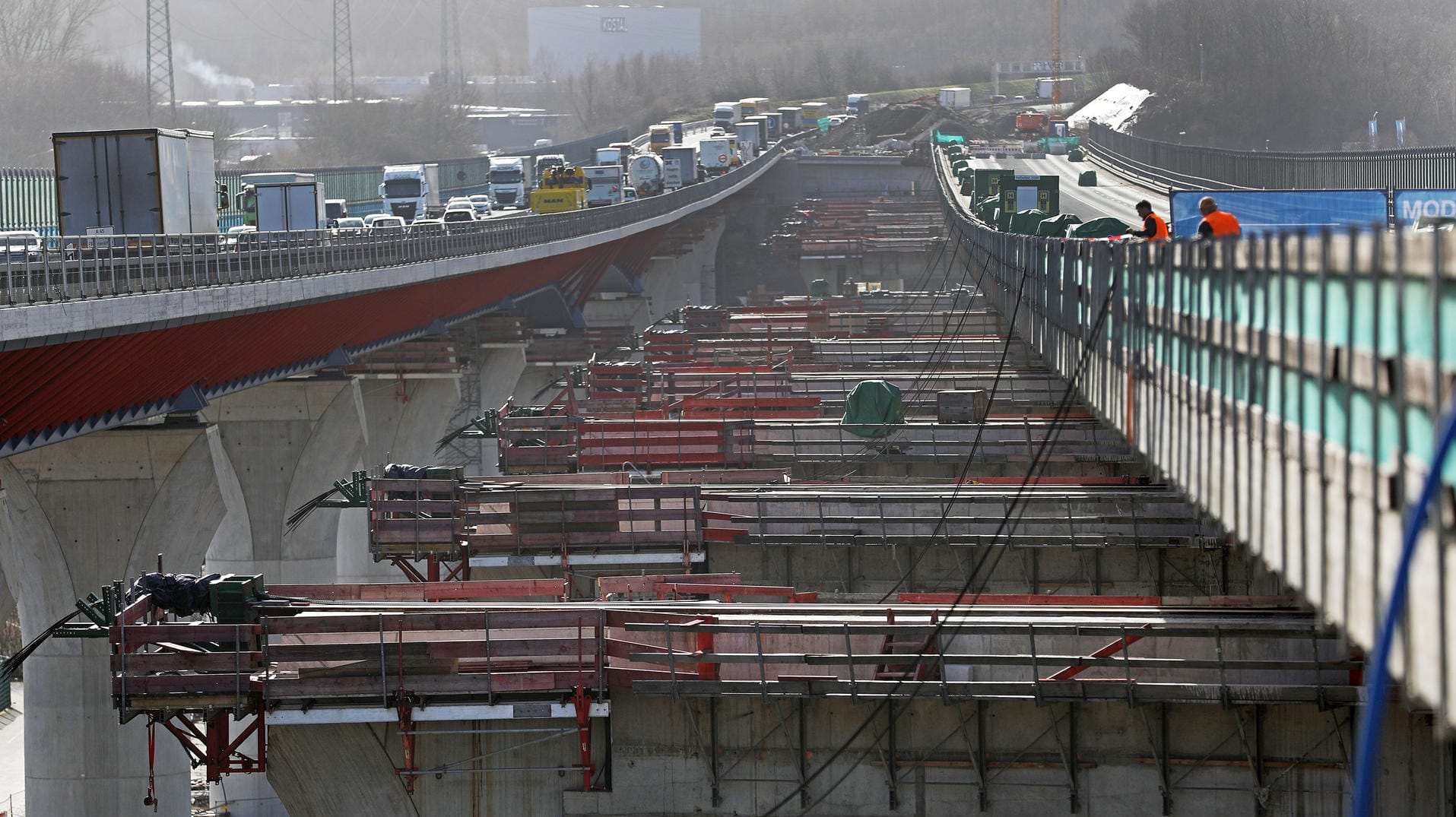 Die neugebaute Brücke (r.) wird zur Fertigstellung der Baustelle versetzt und dabei von provisorischen Pfeilern auf großen Schlitten um etwa 20 Meter in ihre endgültige Position bewegt.