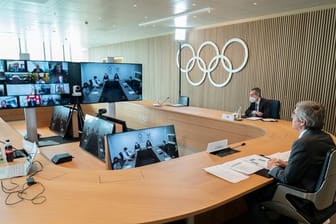 Thomas Bach (r), Präsident des Internationalen Olympischen Komitees (IOC), nimmt an der Sitzung der Exekutive des IOC per Video teil.