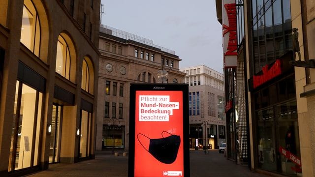 In der Kölner Fußgängerzone wird auf die Maskenpflicht hingewiesen.