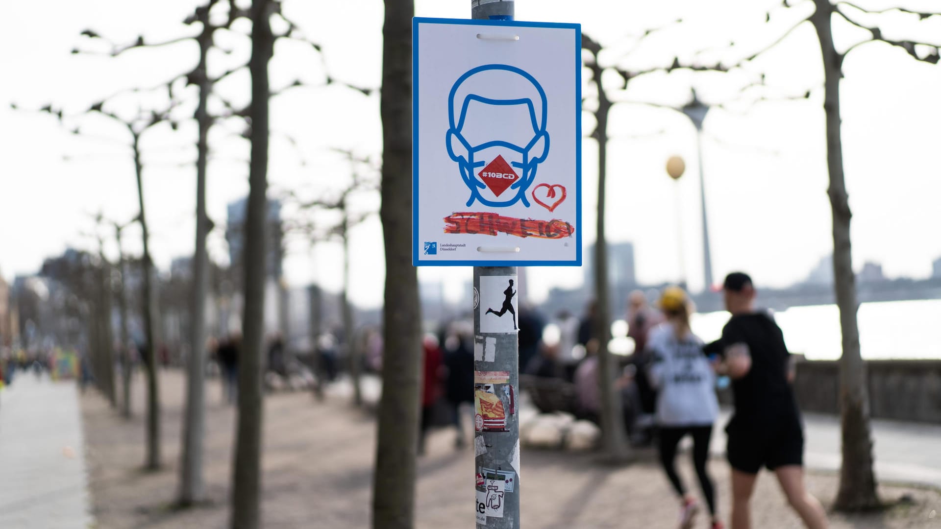 Ein Schild weist auf die Maskenpflicht am Rhein hin: Die Regeln wurden nun örtlich und zeitlich ausgeweitet. Ein Schild weist auf die Maskenpflicht am Rhein hin: Die Regeln wurden nun örtlich und zeitlich ausgeweitet.