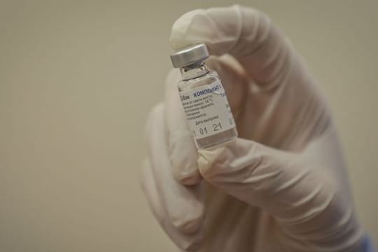Ein Sanitäter hält eine Ampulle mit dem russischen Corona-Impfstoff Sputnik V.