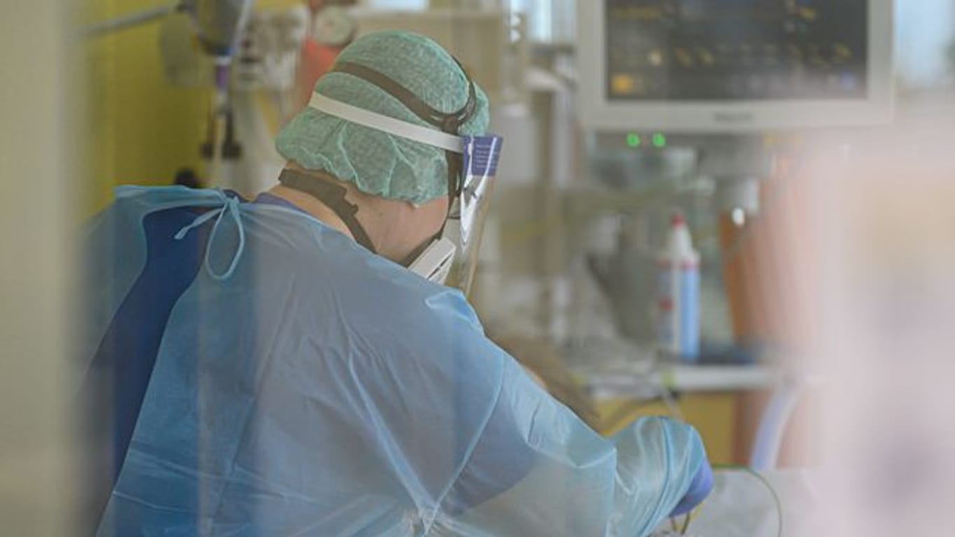 Ein Intensivpfleger ist auf der Covid-19 Intensivstation mit der Versorgung von Corona-Patienten beschäftigt.