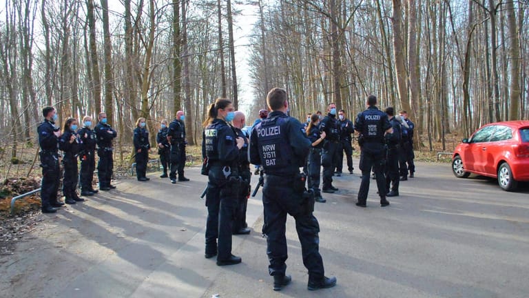 Polizisten stehen auf einem Parkplatz in einem Waldstück bei Köln: 25 Beamte durchkämmten in Höhe der Haltestelle "Stüttgenhof" den Wald nach Spuren des mutmaßlichen Vergewaltigers.