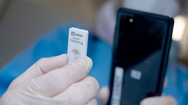 Eine Mitarbeiterin scannt einen Schnelltest, damit das Ergebnis an die getestete Person geschickt werden kann.