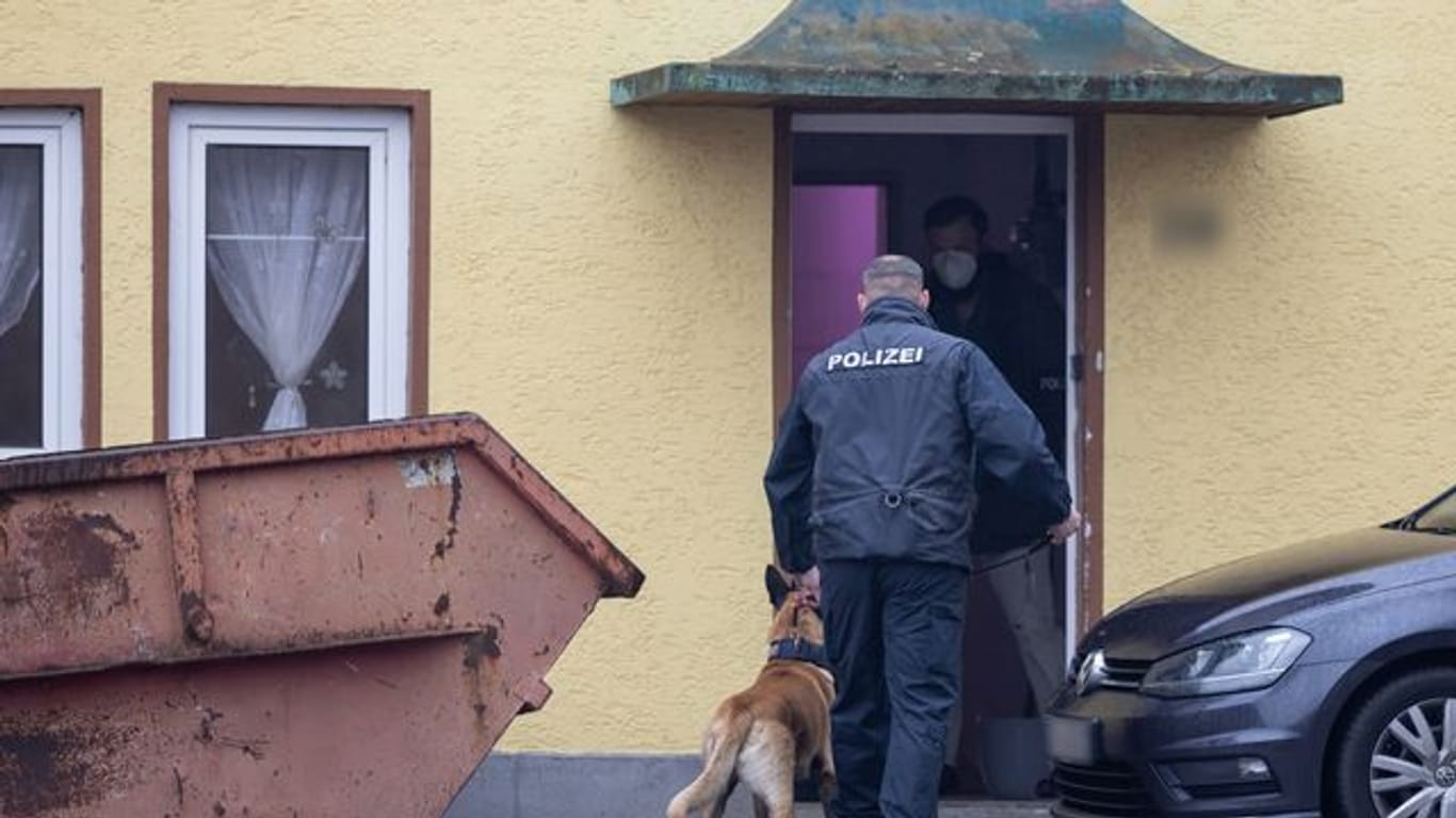 Ein Polizist geht mit einem Drogenspürhund in ein Haus im thüringischen Ballstädt.