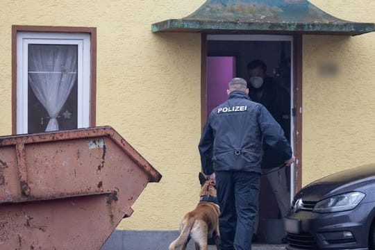 Ein Polizist geht mit einem Drogenspürhund in ein Haus im thüringischen Ballstädt.