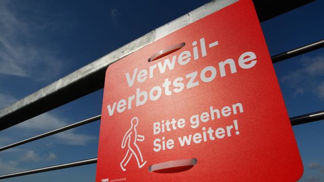 Ein Schild weist auf das "Verweilverbot" hin: In Düsseldorf ist ein Eilantrag gegen das Verbot erfolglos geblieben. Damit tritt das Verbot nun erstmals in Kraft.