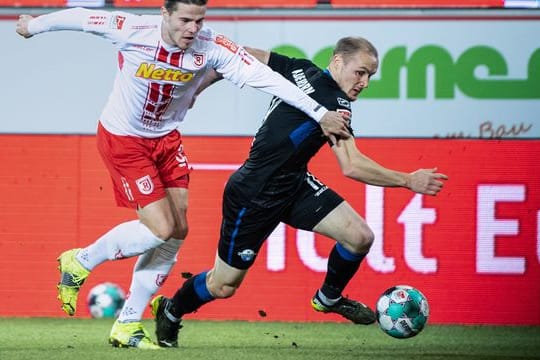 Jan Elvedi von Jahn Regensburg (l) und Sven Michel vom SC Paderborn im Zweikampf um den Ball.