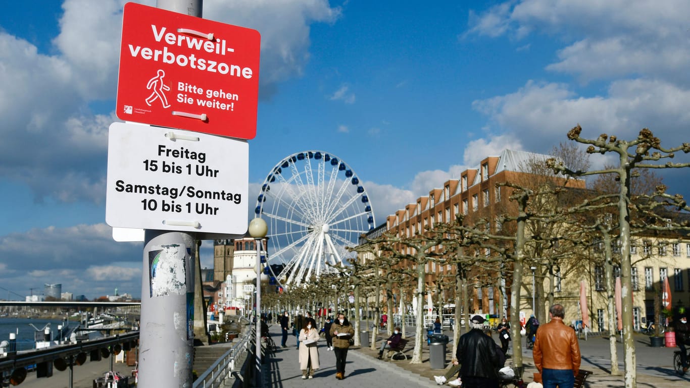 "Bitte gehen Sie weiter" steht auf einem Schild: Aufhalten an der Rheinuferpromenade ist nun am Wochenende verboten.
