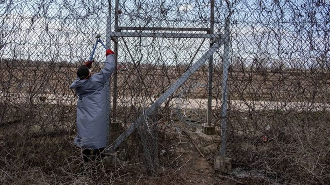 Ein Migrant versucht, an der türkisch-griechischen Grenze bei Pazarkule mit einer Drahtschere den Zaun durchzuschneiden.