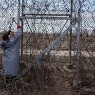 Ein Migrant versucht, an der türkisch-griechischen Grenze bei Pazarkule mit einer Drahtschere den Zaun durchzuschneiden.