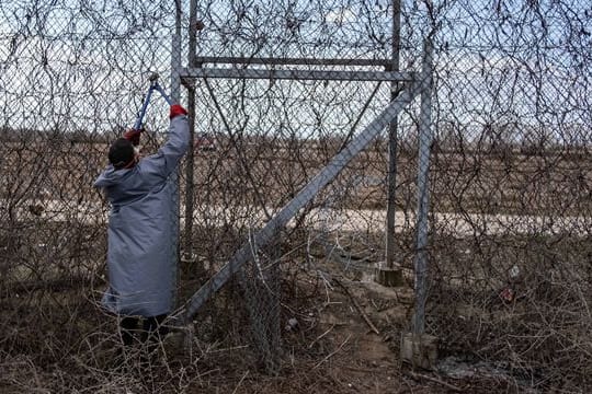 Ein Migrant versucht, an der türkisch-griechischen Grenze bei Pazarkule mit einer Drahtschere den Zaun durchzuschneiden.