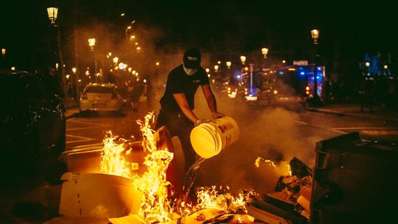 Ein Mann versucht bei den Protesten in Barcelona, ein Feuer zu löschen.