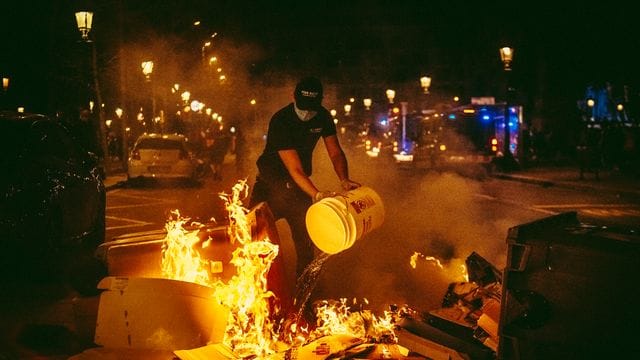 Ein Mann versucht bei den Protesten in Barcelona, ein Feuer zu löschen. Ein Mann versucht bei den Protesten in Barcelona, ein Feuer zu löschen.