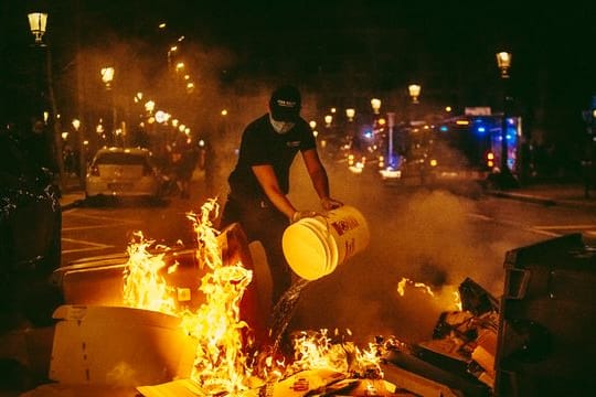 Ein Mann versucht bei den Protesten in Barcelona, ein Feuer zu löschen.