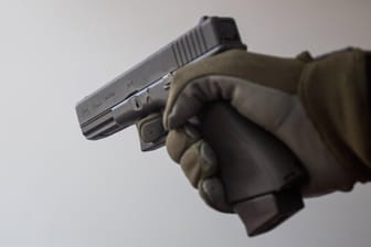 Eine Person hält eine Pistole in der Hand (Symbolbild): In Frankfurt wurden zwei Wettbüros überfallen.