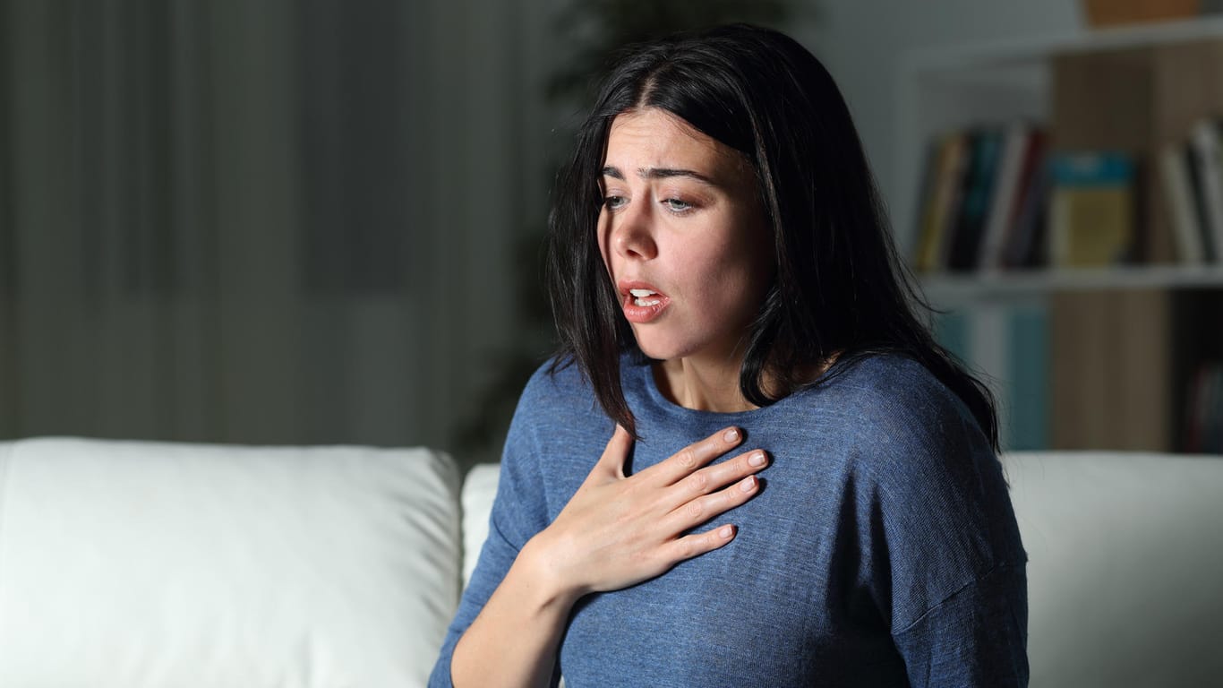 Eine junge Frau ring nach Luft: Plötzliche Atemnot und ein Engefühl in der Brust sind typische Symptome für Asthma.