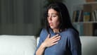 Eine junge Frau ring nach Luft: Plötzliche Atemnot und ein Engefühl in der Brust sind typische Symptome für Asthma.