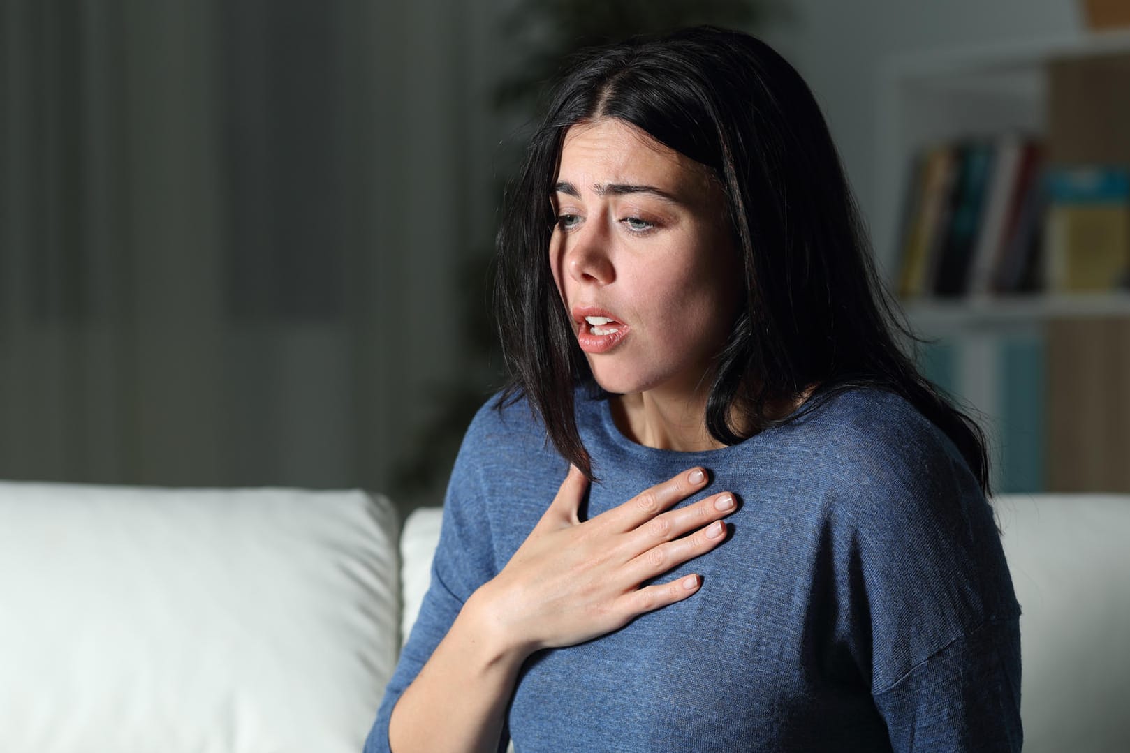 Eine junge Frau ring nach Luft: Plötzliche Atemnot und ein Engefühl in der Brust sind typische Symptome für Asthma.