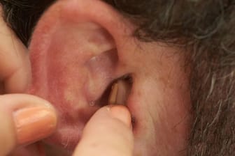 Ein Hörgerät wird in ein Ohr eingesetzt.