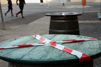 Kein gemütliches Beisammensein: Mit einem rot-weißen-Flatterband sind Stehtische an der Promenade des Ostseebades Warnemünde abgeklebt.