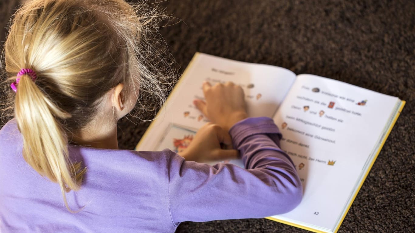 Ein Mädchen liest in einem Buch (Symbolbild): Die Ankerklassen sollen einigen Kindern den Übergang von der Kita in die Schule erleichtern.