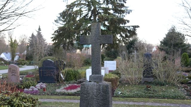Ein steinernes Kreuz ist auf einem Friedhof zu sehen