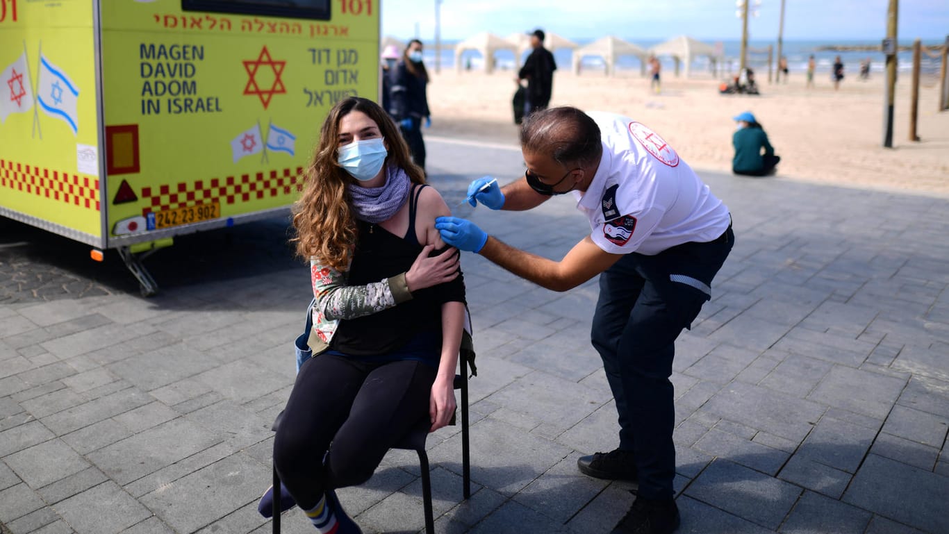 Impfen am Strand: In Tel Aviv gibt ein Mitarbeiter der Hilfsorganisation "Magen David Adom" einer jungen Frau die Impfung.